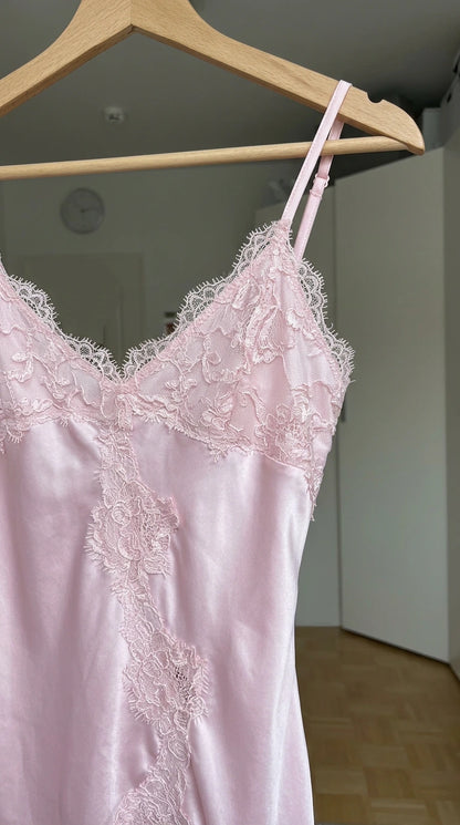 Close-up of delicate floral eyelash lace trim on light pink satin camisole bodice