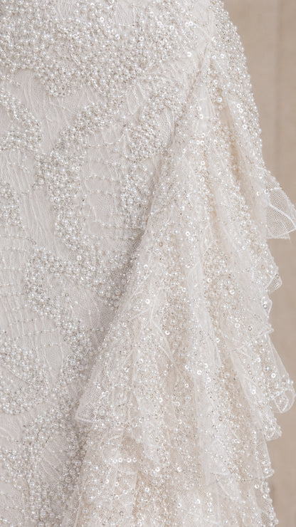 Close-up detail of textured sequin lace fabric and cascading tiered ruffles