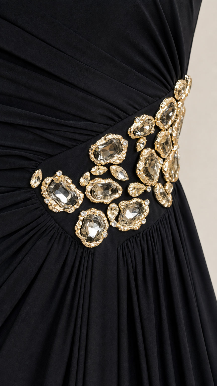Close-up of gathered fabric and gemstone embellishment on black dress