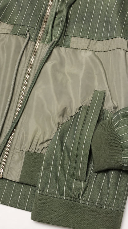 Close-up detail of zipper, ribbed cuffs, and contrast panels on olive green jacket