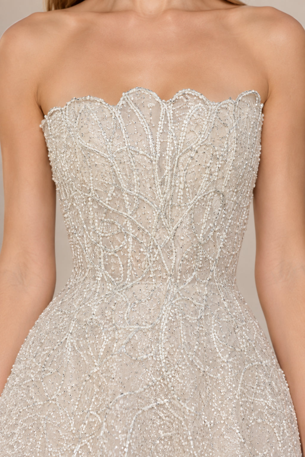 Close-up of silver strapless bodice showing intricate scalloped neckline and beadwork detail