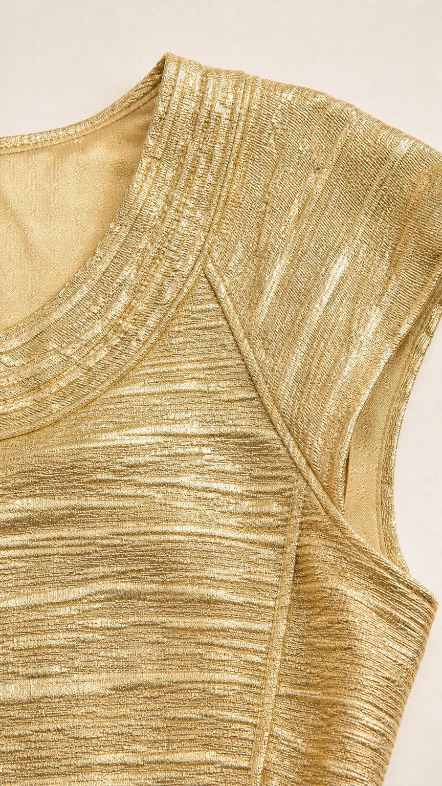Close-up detail of textured metallic gold knit fabric and neckline seam