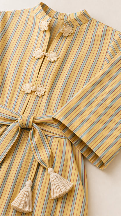 Close-up detail of mandarin collar, knot button closures, and tassel belt on yellow striped dress