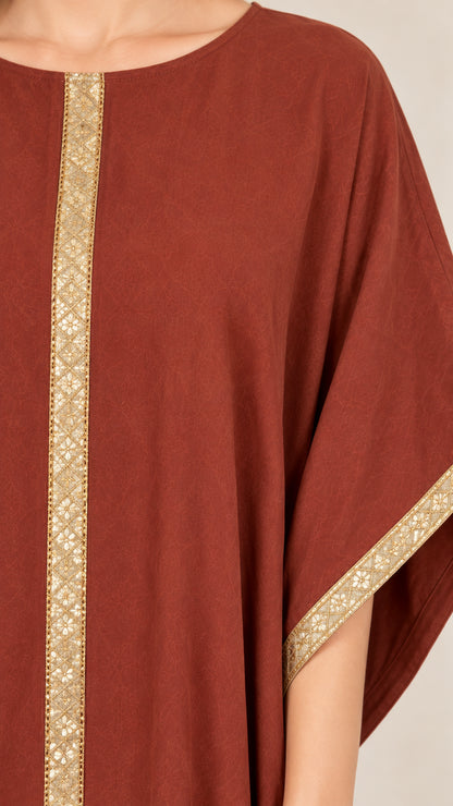 Close-up detail of ornate gold embroidered trim on neckline and cuff of rust dress