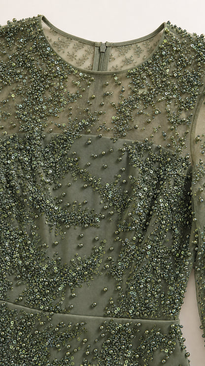 Close-up detail of green illusion mesh fabric with intricate bead and sequin embellishments