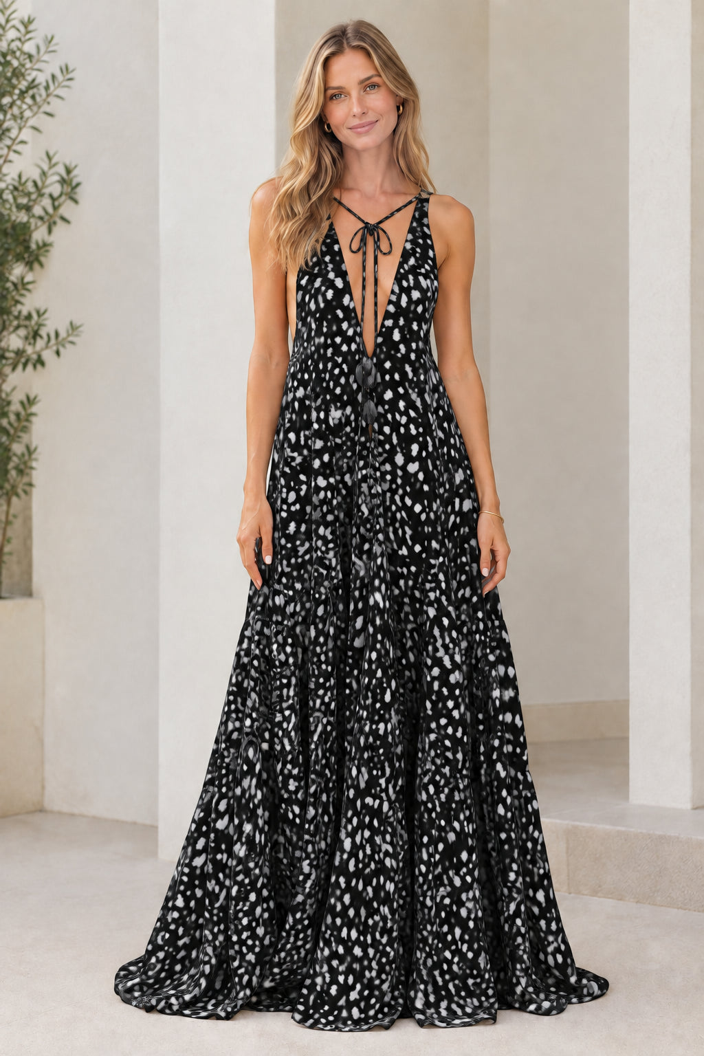 Model wearing black dotted print sleeveless plunge tiered maxi dress