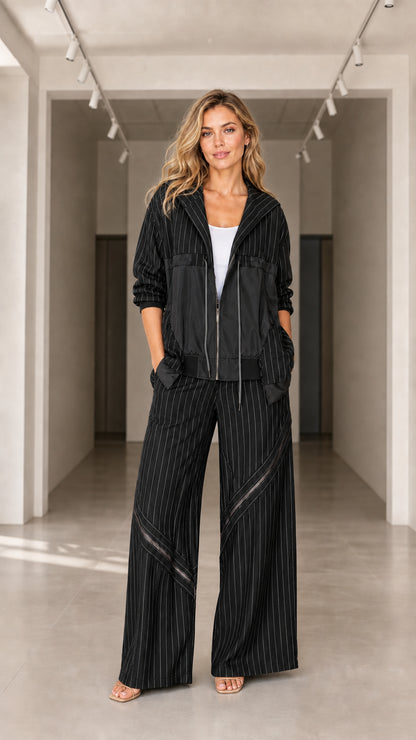 Front view of model wearing black pinstripe hooded jacket and wide-leg trousers set