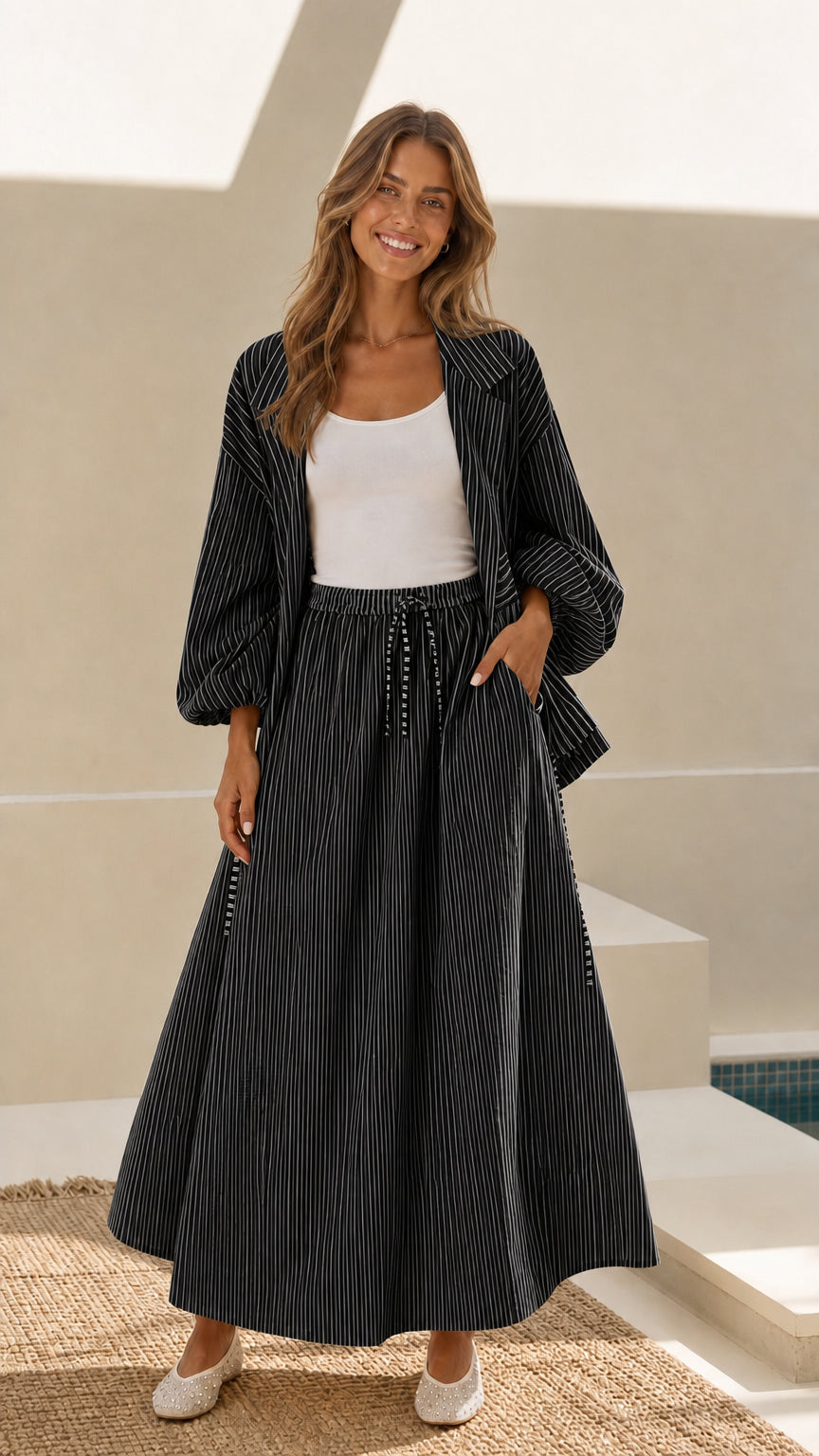 Model wearing black and white striped open-front jacket and maxi skirt set