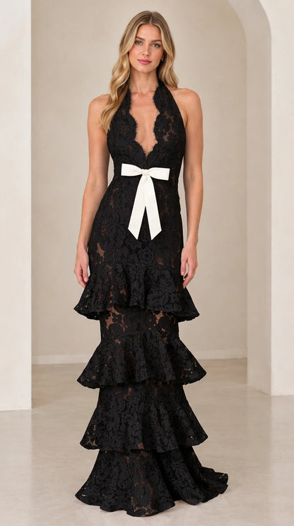 Front view of model wearing Black halter tiered floral lace gown with contrasting waist bow
