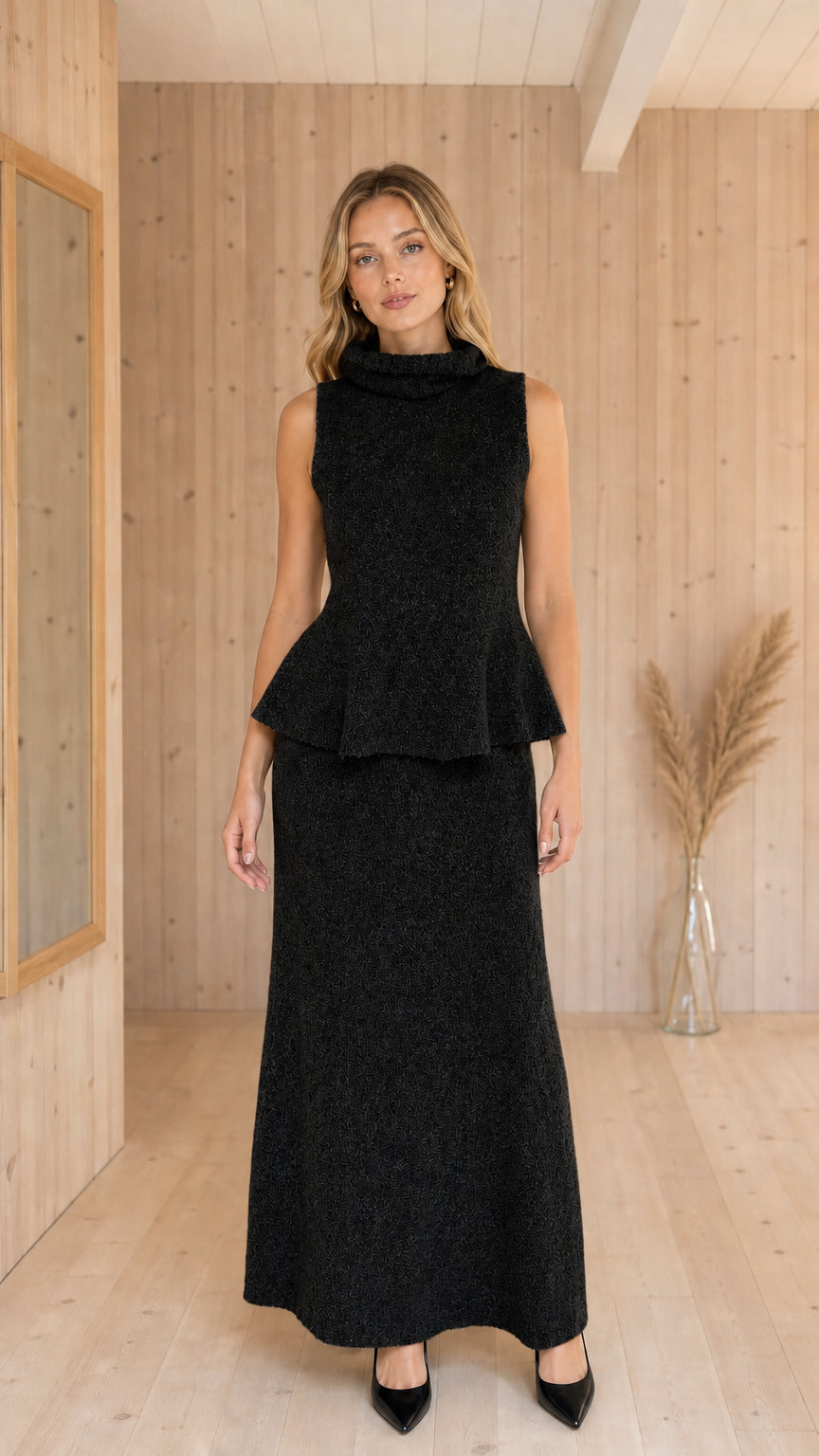 Front view of woman wearing Black sleeveless peplum top and maxi skirt knit set