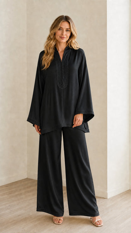 Full-length view of woman wearing the black embroidered tunic and wide-leg pants set