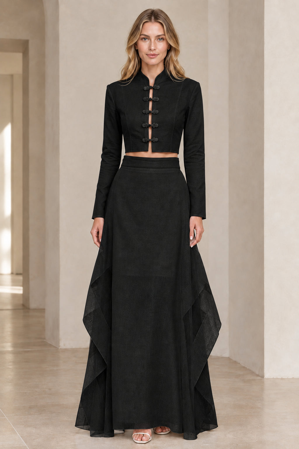 Front view of model wearing black frog button crop top and layered maxi skirt set