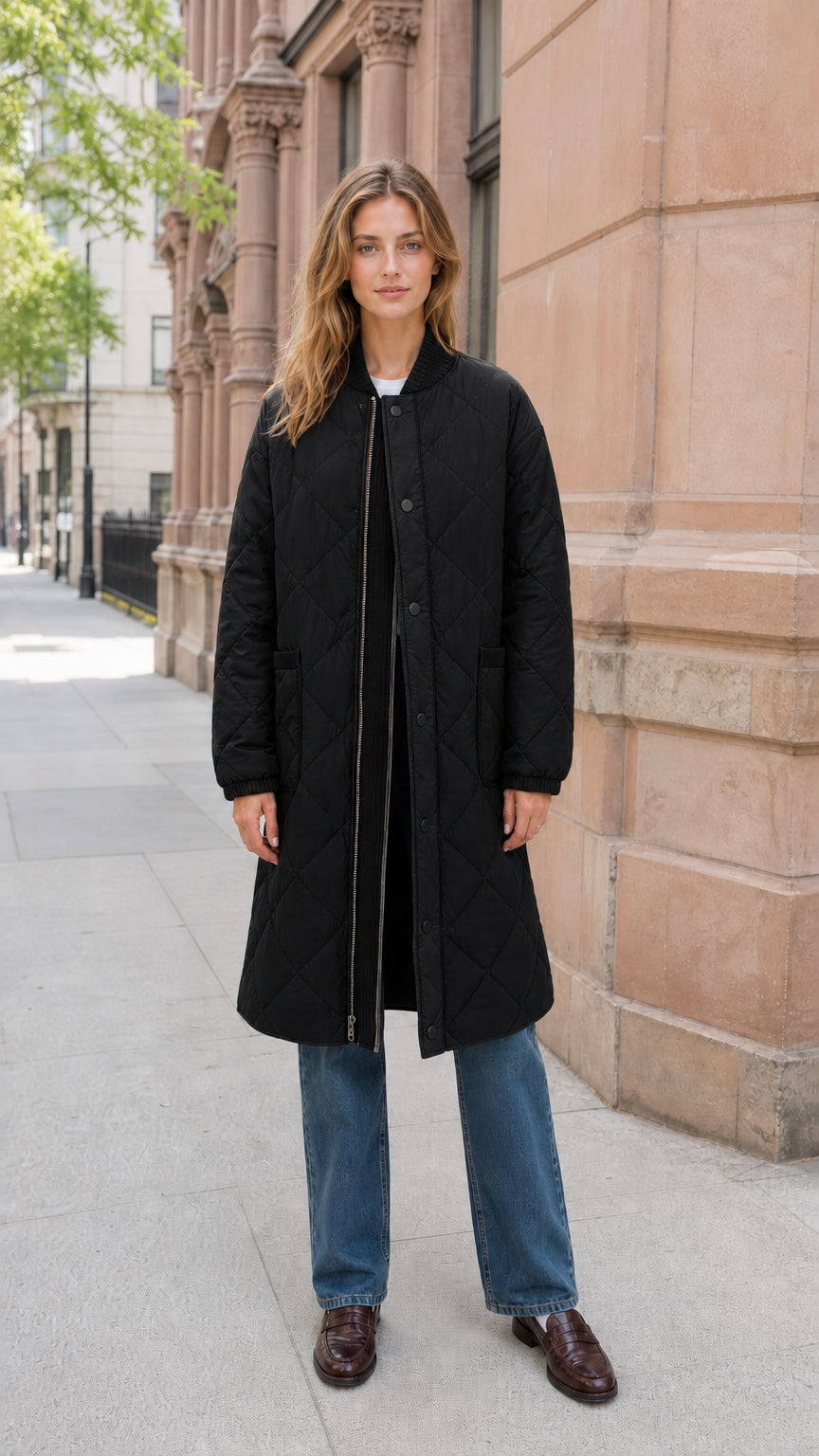 Front view of model wearing black longline diamond quilted bomber coat