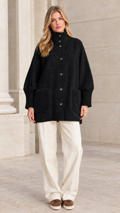 Full front view of a woman wearing a black mock neck button-down jacket