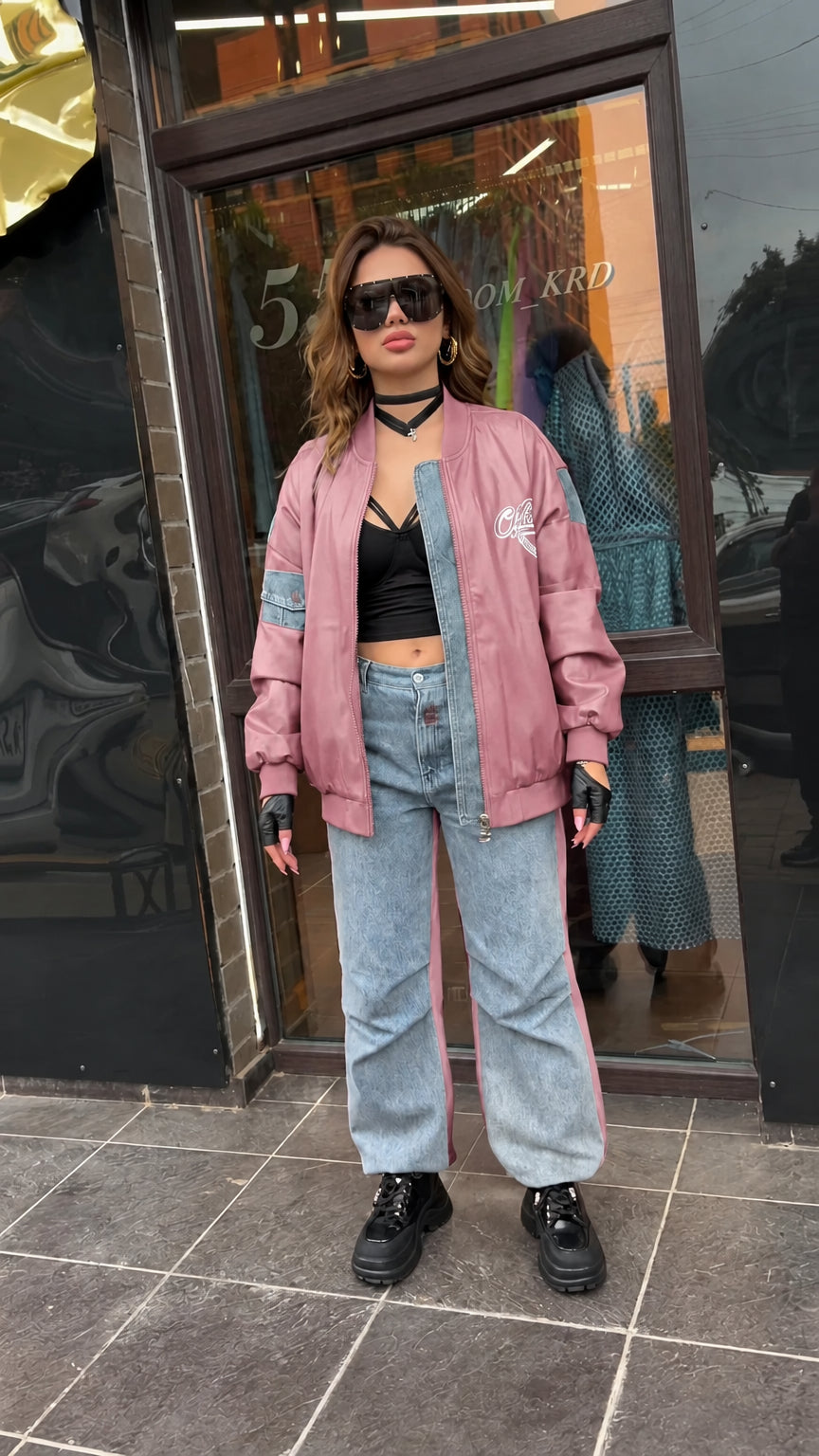 Full-length view of dusty pink faux leather bomber jacket paired with wide-leg jeans