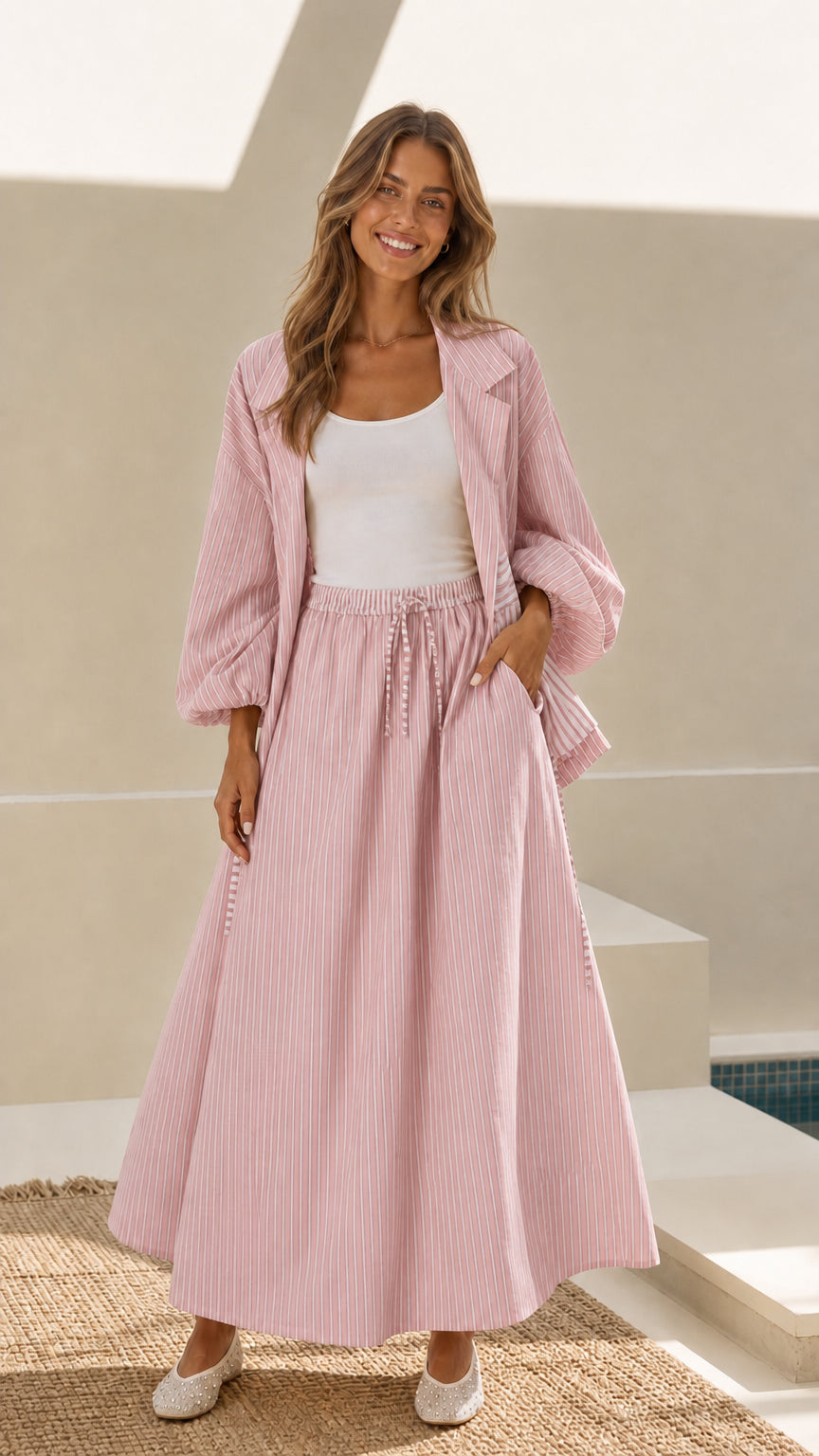 Model wearing light pink striped open-front jacket and maxi skirt set