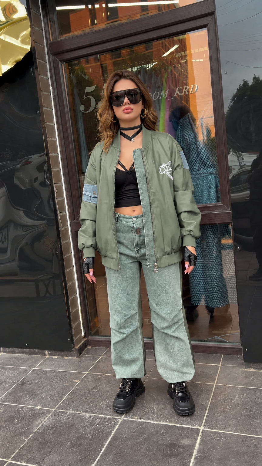 Full-length view of sage green faux leather bomber jacket with washed denim panels