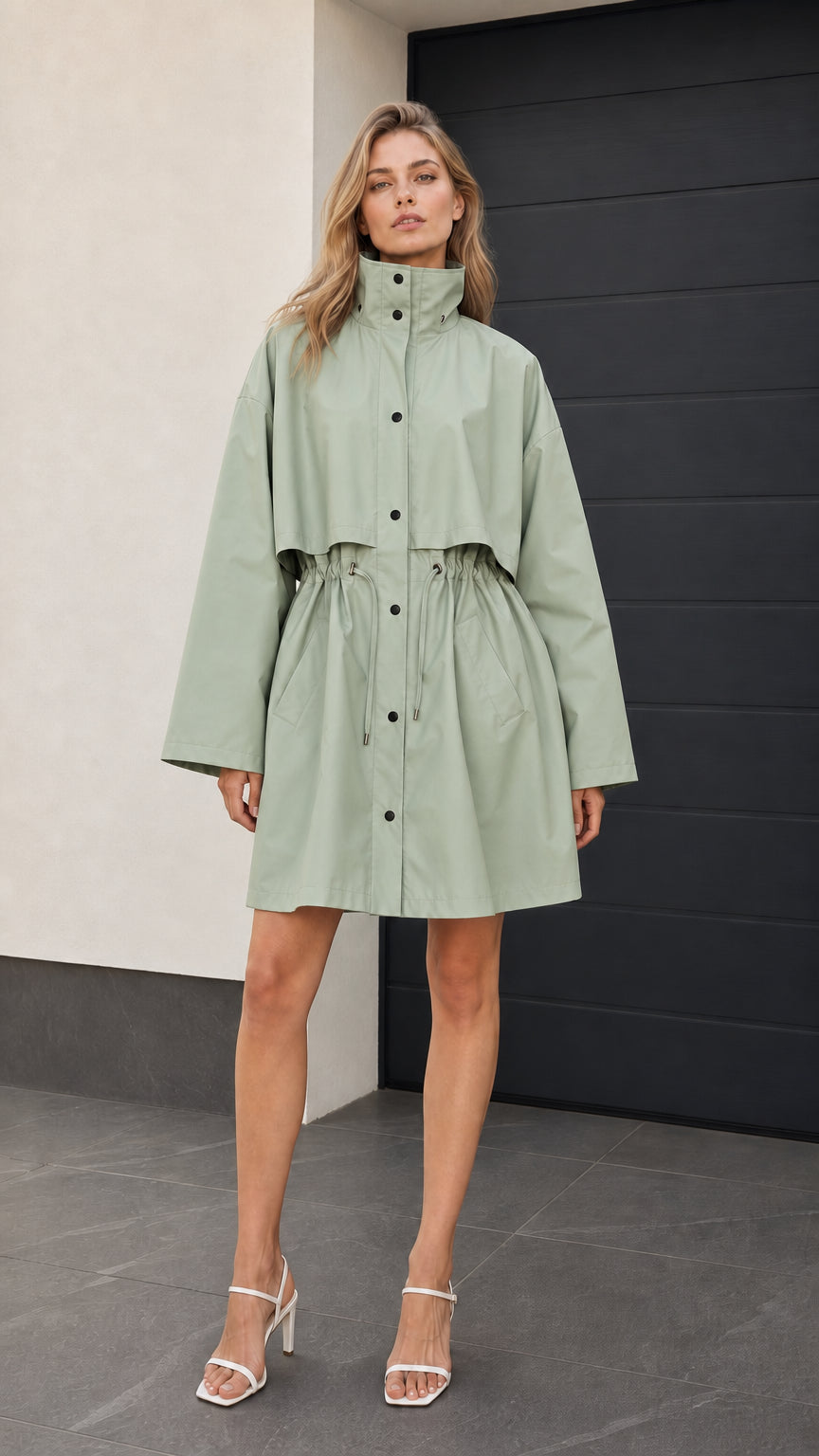 Front full-length view of woman wearing sage green drawstring parka jacket