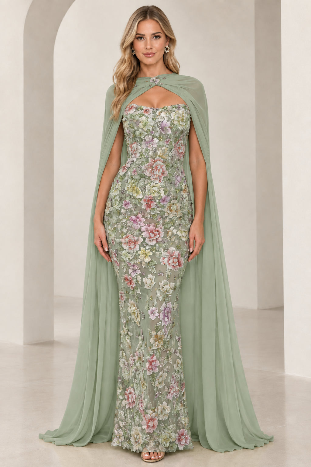 Model wearing sage green floral embroidered strapless gown with elegant chiffon cape