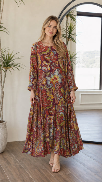Front view of woman wearing burgundy multi paisley tiered long sleeve maxi dress