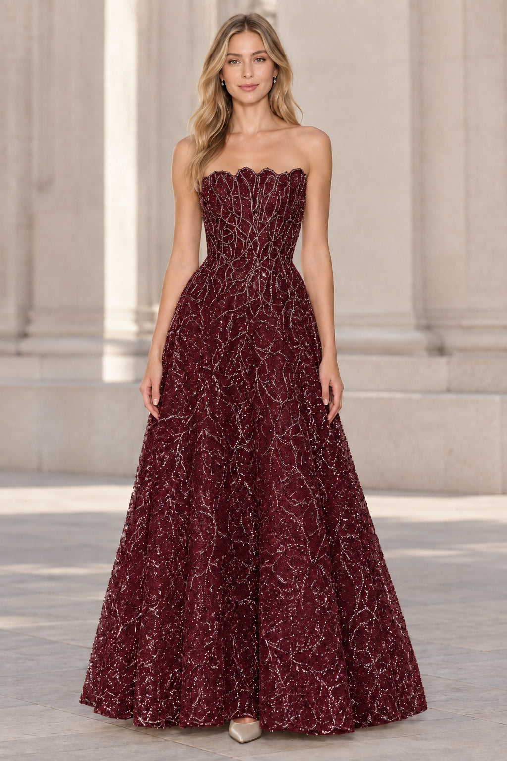 Front view of model wearing burgundy strapless embellished A-line evening gown