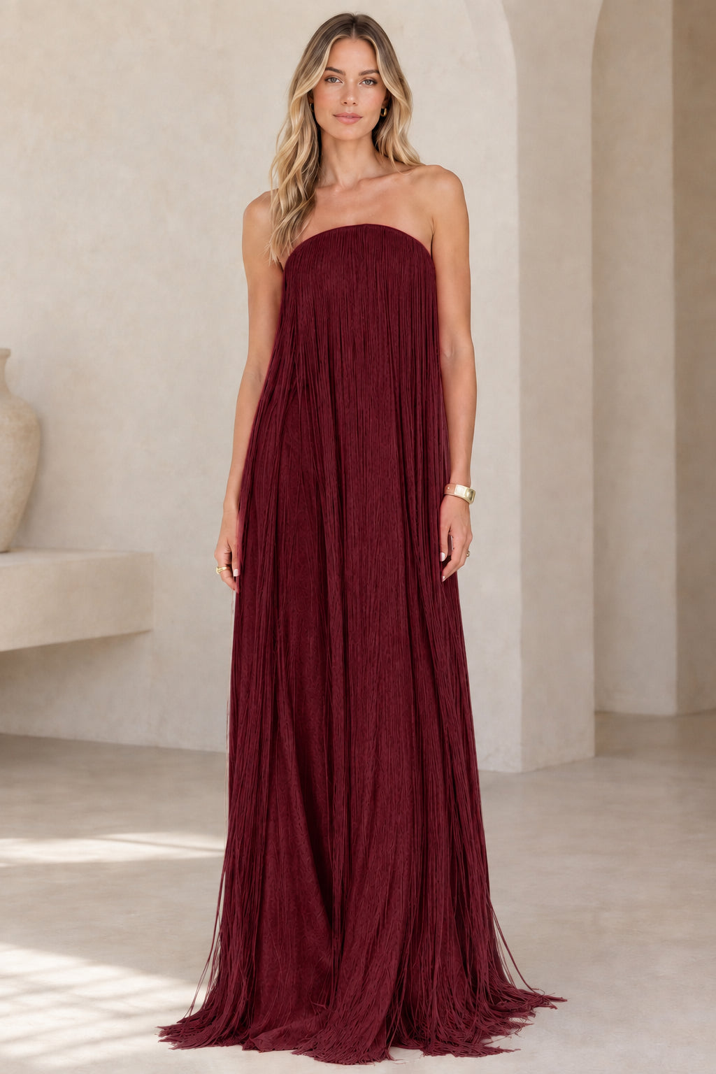 Full-length view of model wearing burgundy red strapless fringe maxi gown