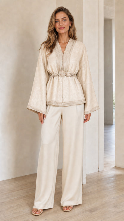 Model wearing cream beige V-neck bell sleeve blouse styled with matching trousers