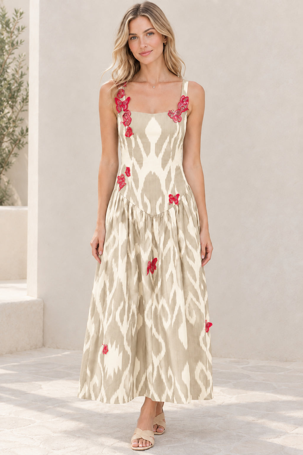 Model wearing beige tan and white ikat print sleeveless maxi dress with butterfly details