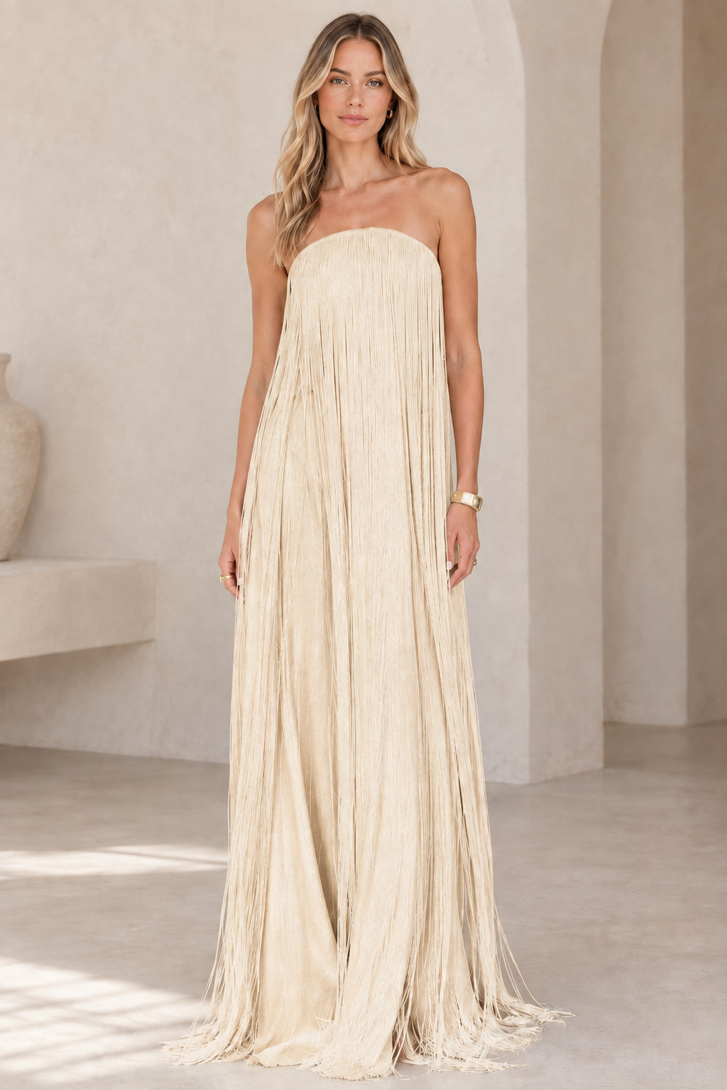 Full-length view of model wearing champagne beige strapless fringe maxi gown